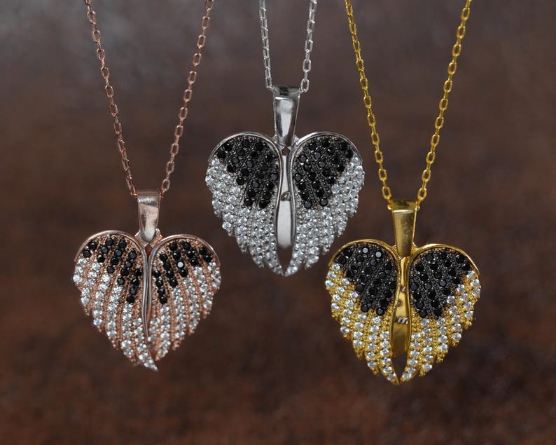 Three heart-shaped pendants with black and white gemstones are displayed against a brown background.