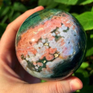 Pink, white and green orbicular ocean jasper sphere