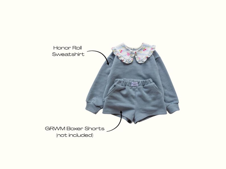 May include: A light blue Honor Roll sweatshirt and matching GRWM boxer shorts. The sweatshirt has a floral-patterned collar. The shorts have pockets and a small label. The set is made of a soft material.
