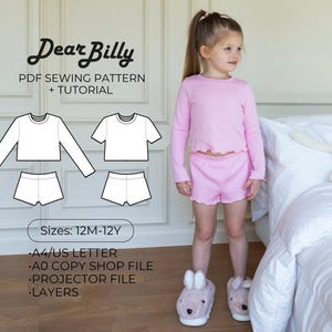 May include: A young girl wearing a pink long-sleeved top and matching shorts. The image also shows a PDF sewing pattern with the text "Dear Billy" and the sizes 12M-12Y. The pattern includes designs for a long-sleeved top, shorts, and a short-sleeved top.