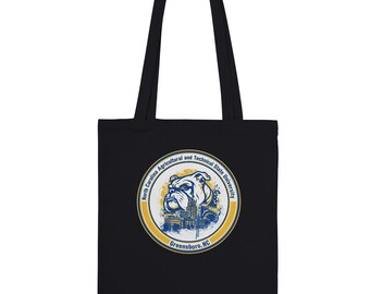 May include: Black tote bag featuring a circular emblem with a bulldog, buildings, and text: "North Carolina Agricultural and Technical State University" and "Greensboro, NC". The bag has two black handles.