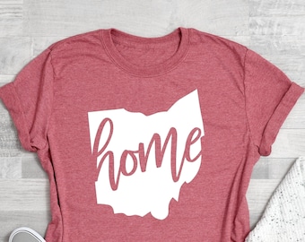 May include: Coral pink t-shirt with a white outline of the state of Ohio and the word "home" written inside the outline.