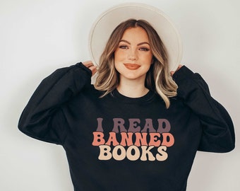 May include: A black sweatshirt with the text "I READ BANNED BOOKS" in a retro font with a gradient of pink, orange, and purple.