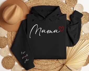 May include: Black hoodie featuring the word "Mama" in white script with a red heart. The left sleeve displays the names "Lisa", "Sarah", and "John" in white script with red hearts. The hoodie is presented on a woven background.
