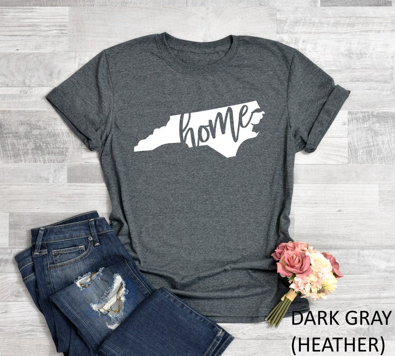 K&ouml;nnte beinhalten: Dunkelgraues T-Shirt mit einem wei&szlig;en Umriss des Bundesstaates North Carolina und dem Wort "home" innerhalb des Bundesstaates.