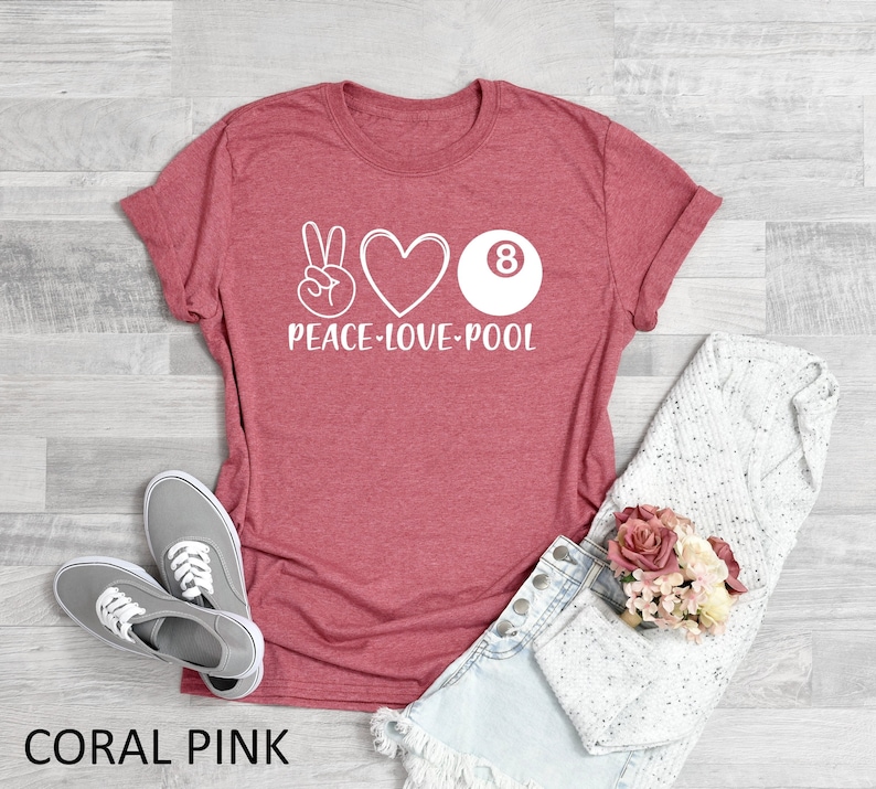 May include: Coral pink t-shirt with a white peace sign, heart, and 8-ball graphic. The text "Peace-Love-Pool" is printed below the graphic.