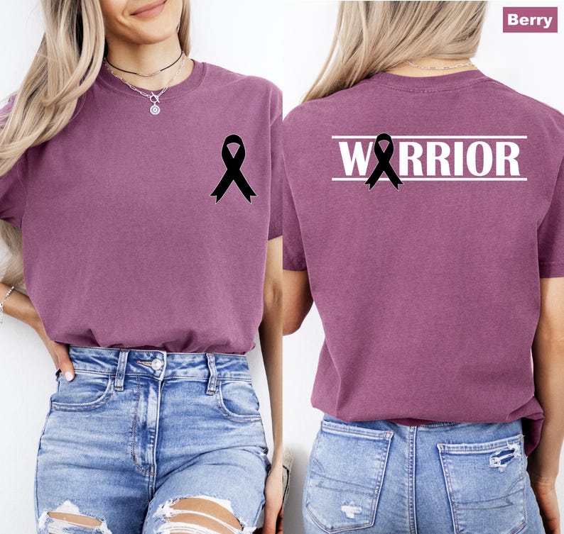 May include: Berry-colored t-shirt with a black ribbon graphic on the front and back. The back of the shirt features the word "WARRIOR" in white block letters above the ribbon. The shirt is made of a soft material.