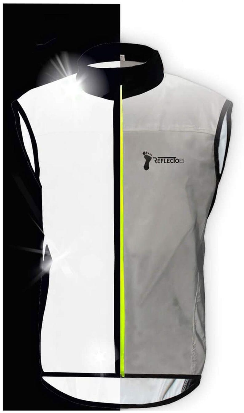 May include: A reflective vest with a black collar and trim, a neon yellow zipper, and the text "REFLECTOES" with a footprint logo. The vest is primarily white and gray, designed for visibility.