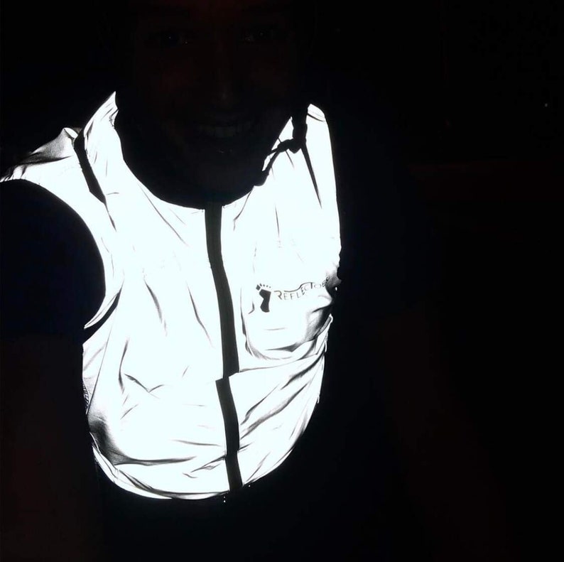 May include: A reflective vest with a zipper closure. The vest is white and has a small logo on the chest. The vest is designed to increase visibility in low-light conditions.