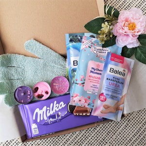 Puede incluir: Una caja de regalo llena de varios productos de ba&ntilde;o y cuerpo, incluyendo bombas de ba&ntilde;o, sales de ba&ntilde;o, un exfoliante para pies y una barra de chocolate. La caja tambi&eacute;n incluye un par de guantes exfoliantes y algunas velas de t&eacute;.