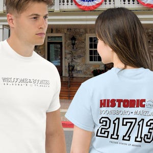 May include: A white ceramic mug with a black handle and the text "But First, Coffee" in a black, bold font. The mug is on a white surface. The mug is 4 inches tall.