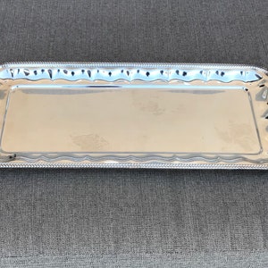 May include: A silver serving tray with a decorative scalloped edge.