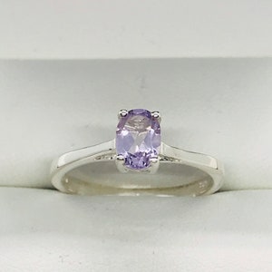 May include: A silver ring with a light purple oval gemstone.