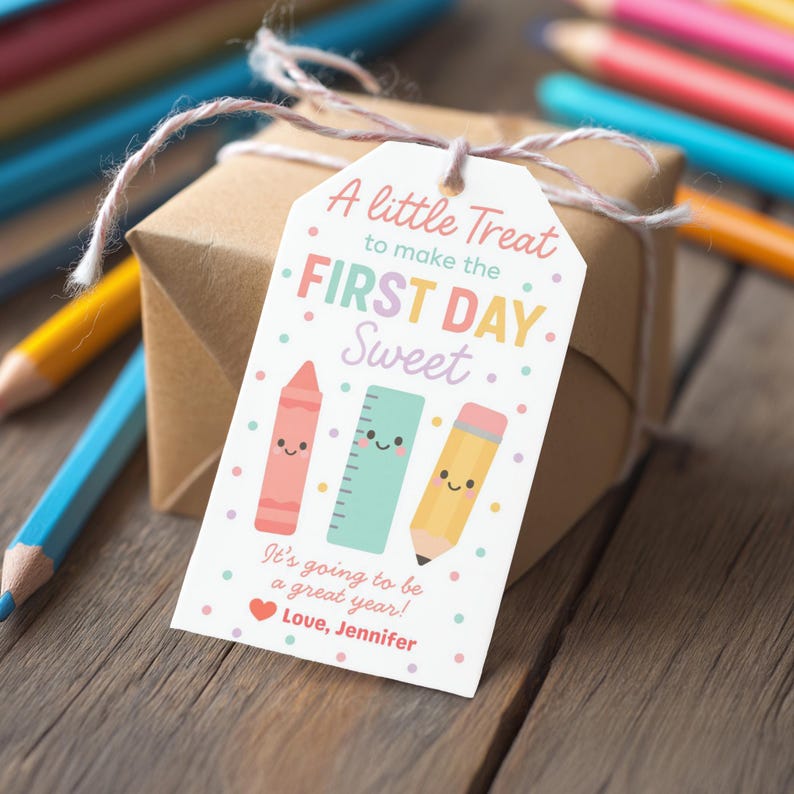 May include: A gift box wrapped in brown paper with a tag that reads "A little Treat to make the FIRST DAY Sweet." The tag features illustrations of a crayon, ruler, and pencil. The text "It's going to be a great year! Love, Jennifer" is also on the tag.