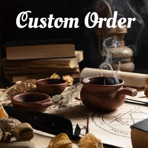 Puede incluir: Un cuenco de arcilla marr&oacute;n con asa que emite humo, acompa&ntilde;ado de dos cuencos m&aacute;s peque&ntilde;os a juego, libros apilados, hierbas secas y un pergamino con un diagrama geom&eacute;trico. El texto dice Custom Order y StayMagicalTarot.