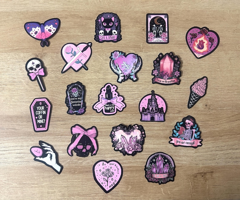 May include: A collection of stickers with a gothic theme, featuring a butterfly, cat, hearts, a skull, a coffin, a lipstick, a castle, and an ice cream cone. Some stickers have text like "Cute & Spooky" and "Your Coffin or Mine?"