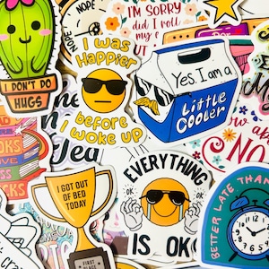 May include: A collection of colorful stickers with various designs and text. Stickers include a cactus, a cooler, a trophy, and an alarm clock. Text includes "I don't do hugs", "I was happier before I woke up", and "Everything is ok".