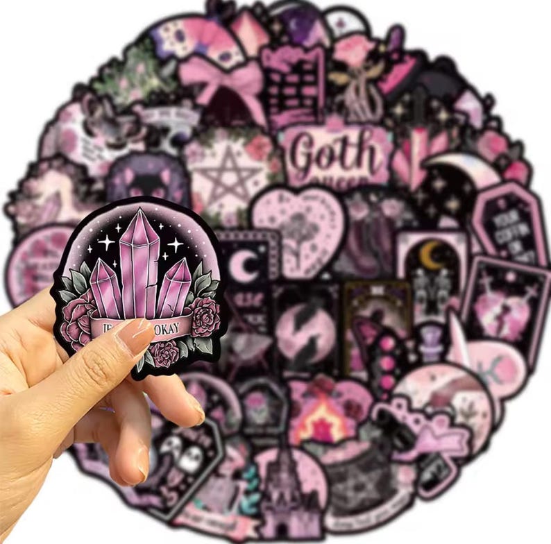 May include: A collection of pink and black goth-themed stickers. One sticker, held by a hand, features pink crystals, roses, and the text "TE OKAY". Other stickers include moons, hearts, stars, and the words "Goth Queen".