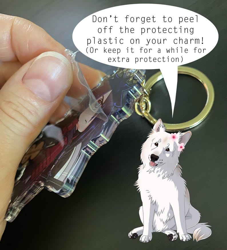 May include: A clear acrylic charm with a character design, attached to a gold-colored keyring. The charm is shown with its protective plastic being peeled off. A cartoon white dog with a flower crown is also in the image.