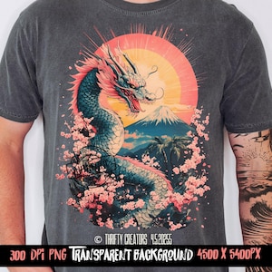 May include: A gray t-shirt with a graphic print of a blue dragon with pink cherry blossoms and a mountain in the background. The dragon is surrounded by a yellow sun and pink cherry blossoms. The text "Thrifty Creators 4.5.2023" is printed on the bottom of the shirt.