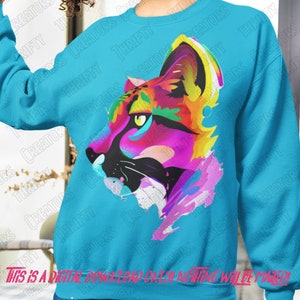 May include: A turquoise blue sweatshirt with a colorful abstract design of a panther's face. The design is made up of bright pink, yellow, blue, and green paint splatters.