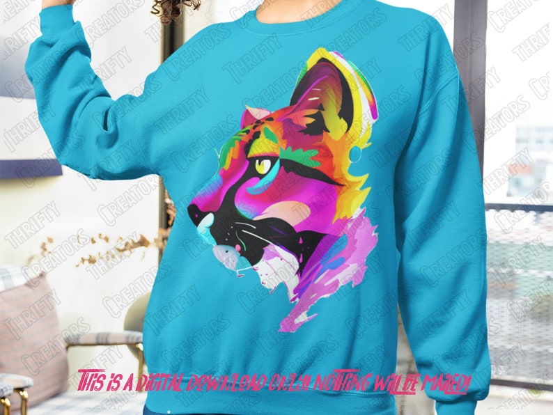 May include: A turquoise blue sweatshirt with a colorful abstract design of a panther's face. The design is made up of bright pink, yellow, blue, and green paint splatters.