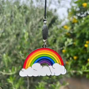 May include: A rainbow-colored metal charm with a white cloud design, hanging from a black string with a black lava rock bead.