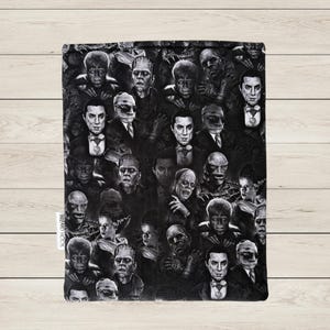 May include: Black and white fabric featuring a collage of classic movie monsters, including Frankenstein's monster, Dracula, and the Mummy. The design is a repeating pattern of various monster portraits. The text "WIZARD HOOK" is visible on the side.