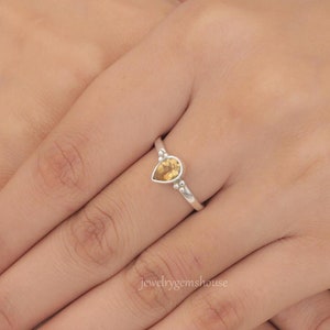 Peut inclure: Une bague en argent avec une pierre précieuse en topaze de forme goutte. La bague a une bande perlée.