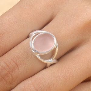 May include: A silver ring with a delicate, open design featuring a pale pink oval gemstone.