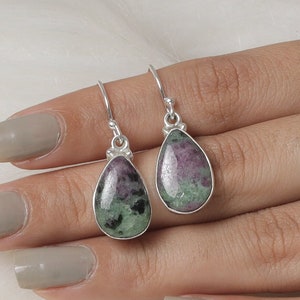 Peut inclure: Une paire de boucles d'oreilles en argent en forme de goutte avec des pierres précieuses vertes et roses.