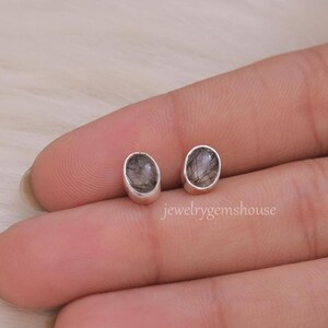 May include: A pair of silver stud earrings with oval-shaped black and clear stones.