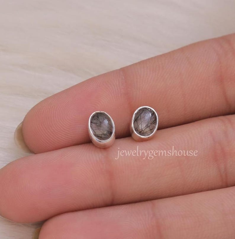 May include: A pair of silver stud earrings with oval-shaped black and clear stones.
