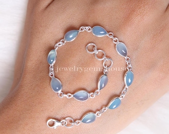 May include: A silver bracelet featuring teardrop-shaped, light blue gemstones. The bracelet is connected by small silver links and has a clasp closure. The jewelry is displayed on a light-colored surface.