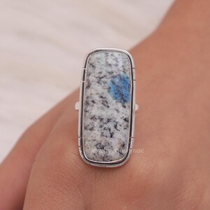 May include: A silver ring with a rectangular blue and white kyanite gemstone. The ring is set in a silver band with a smooth finish.