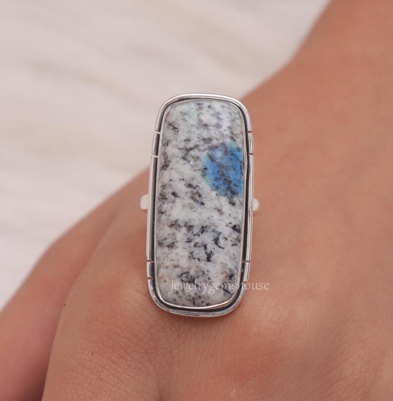 May include: A silver ring with a rectangular blue and white kyanite gemstone. The ring is set in a silver band with a smooth finish.