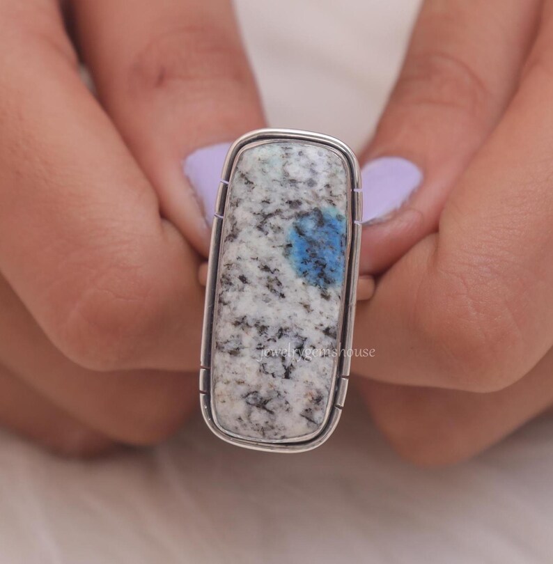 May include: A silver ring with a rectangular blue and white stone. The stone has a speckled pattern.