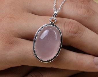 May include: A silver chain necklace with a rose quartz pendant. The pendant is oval shaped and has a silver bezel setting.