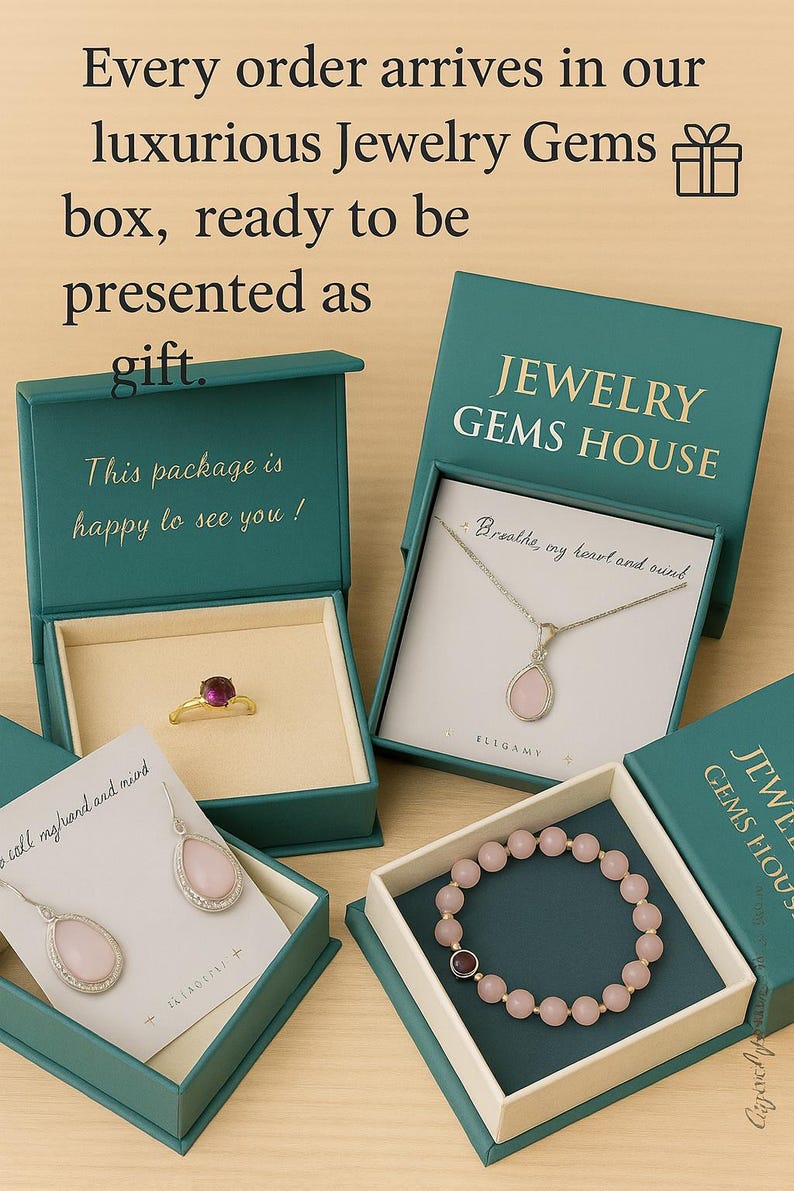 Puede incluir: Cuatro cajas de joyer&iacute;a color verde azulado que contienen un anillo dorado con una piedra roja oscura, un collar plateado con un colgante de l&aacute;grima, pendientes de l&aacute;grima plateados y una pulsera de cuentas rosas. Texto Jewelry Gems House.