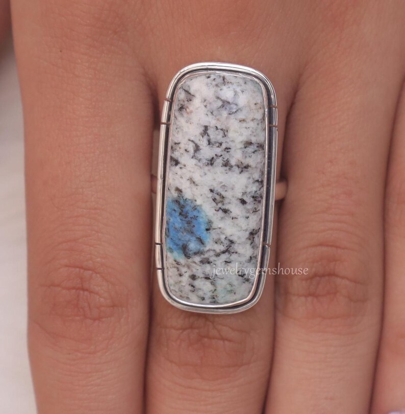 May include: A silver ring with a rectangular blue and white stone. The stone has a speckled pattern.