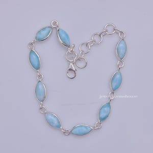 Puede incluir: Una pulsera de plata con piedras preciosas ovaladas de color azul claro. Las piedras est&aacute;n engastadas en biseles individuales de plata y unidas con una cadena de plata. La pulsera tiene un cierre de mosquet&oacute;n.
