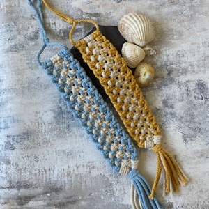 May include: Two macrame bookmarks with tassels. One is blue and white, the other is yellow and white.