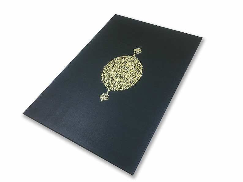 K&ouml;nnte beinhalten: Eine rechteckige schwarze Mappe mit matter Oberfl&auml;che und einem mittig platzierten, komplexen Goldfolien-Emblem. Das Emblem ist ein ovales, kunstvolles Filigran-Design mit spitzen dekorativen Verzierungen oben und unten, zentriert auf dem Vorderdeckel.