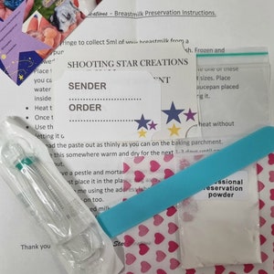 May include: A blue and white instruction sheet with the title "Shooting Star Creations" and a section for "Sender" and "Order". The sheet is surrounded by various items, including a small plastic syringe, a blue plastic stick, a small white bag of powder, and a sheet of paper with pink hearts printed on it.