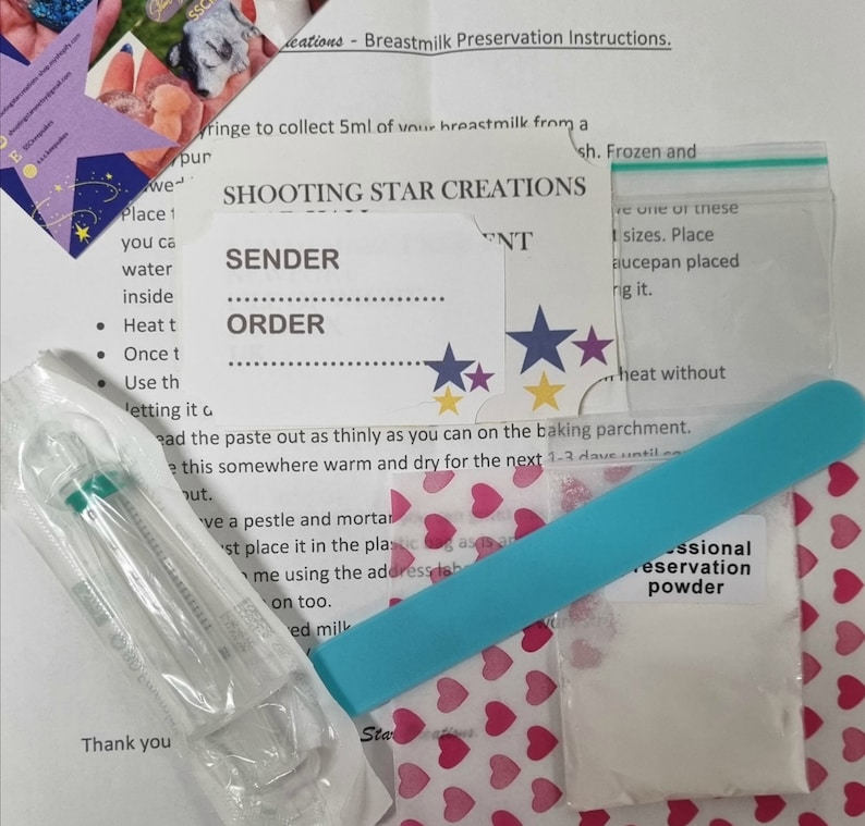 May include: A blue and white instruction sheet with the title "Shooting Star Creations" and a section for "Sender" and "Order". The sheet is surrounded by various items, including a small plastic syringe, a blue plastic stick, a small white bag of powder, and a sheet of paper with pink hearts printed on it.