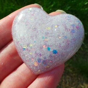 May include: A white heart-shaped resin paperweight with iridescent glitter embedded in the resin.