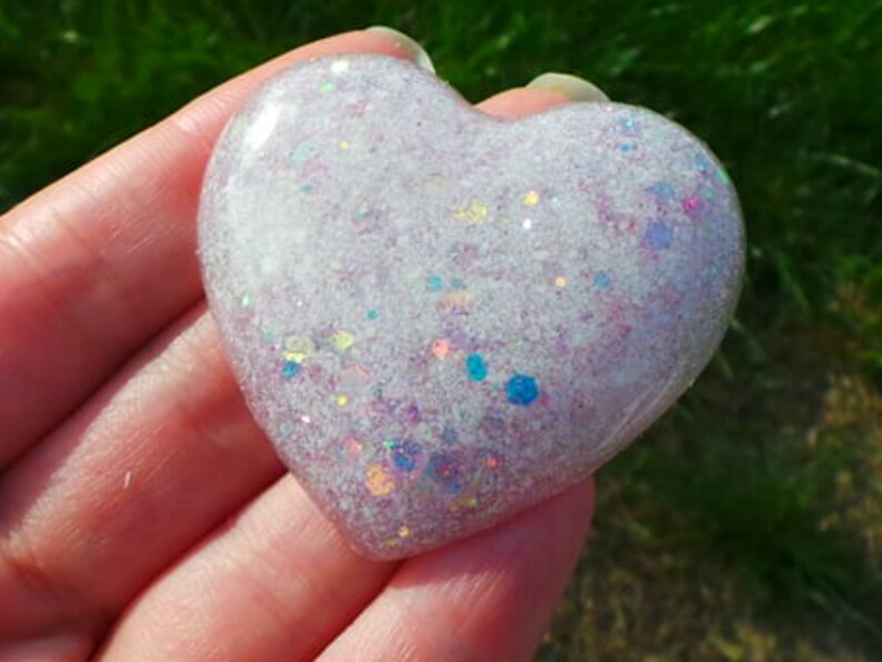 May include: A white heart-shaped resin paperweight with iridescent glitter embedded in the resin.