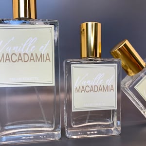 Three glass bottles of perfume, 100ml, 50ml and 30ml, with gold caps and labels that say "Vanille et MACADAMIA" and "EAU DE TOILETTE".