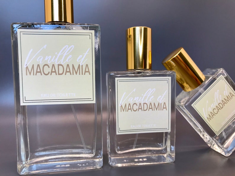 Three glass bottles of perfume, 100ml, 50ml and 30ml, with gold caps and labels that say "Vanille et MACADAMIA" and "EAU DE TOILETTE".