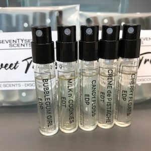 May include: A set of six small glass bottles with black caps and labels. The labels have the names of different scents, including "Cherry Floats", "Creme de Pistache", "Candy Floss", "Milk 'n' Cookies", "Bubblegum Girl", and "Sweet Treats Discovery Pack".